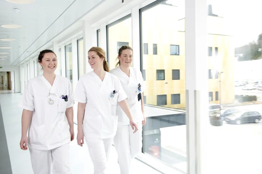 Tre sykepleiere går i en korridor