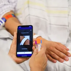 Bilde av et pasientbånd og en mobiltelefon som skanner båndet.